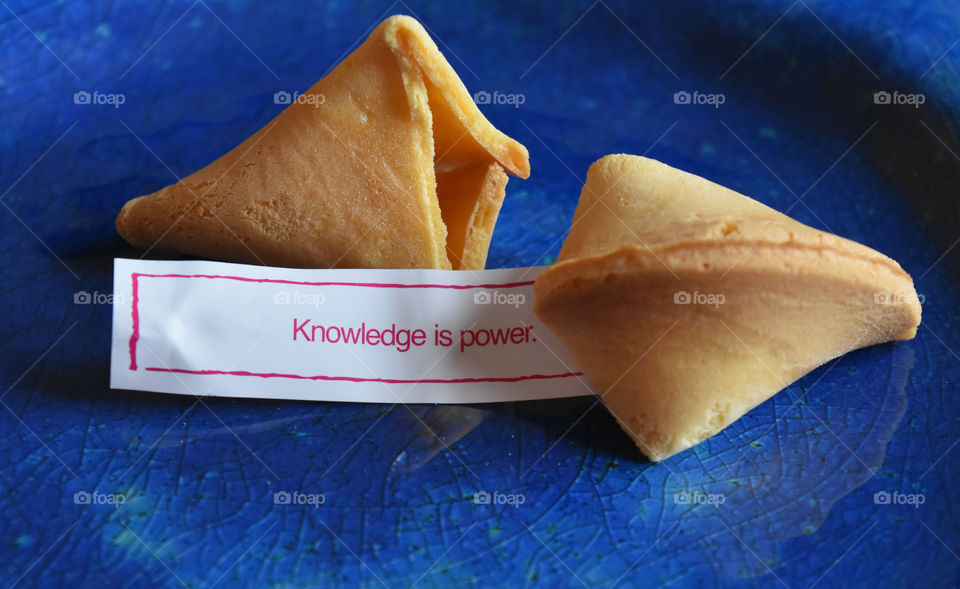 Fortune cookie with fortune on a blue plate