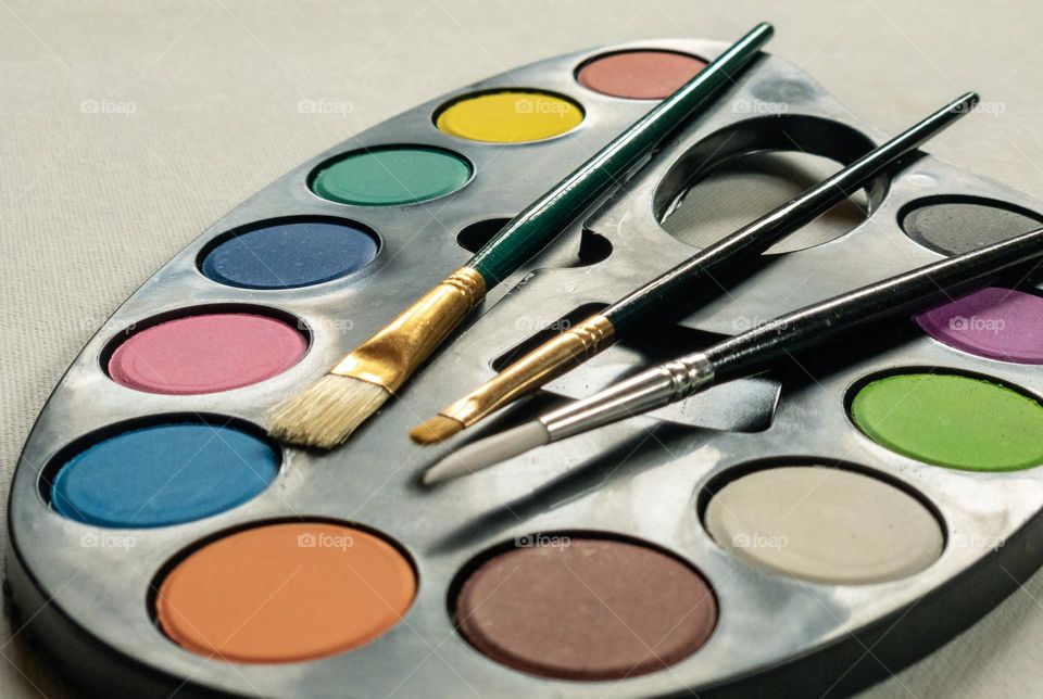 Circles of coloured paint with brushes on a palette 
