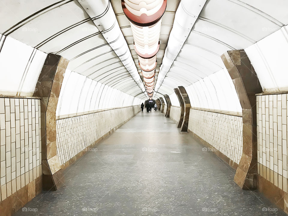 Symmetrical geometric view of a subway tunnel with tiny humans in the city 