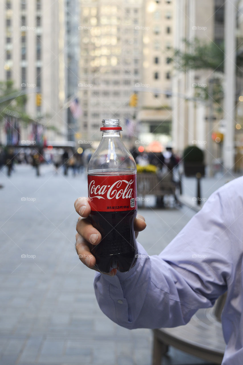 Man holding a coke bottle on a city street
