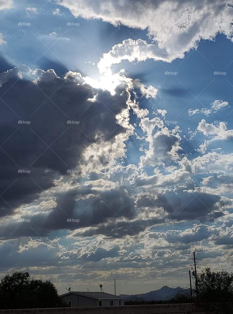 "Window to heaven" Sun shining from behind the clouds against a very blue sky