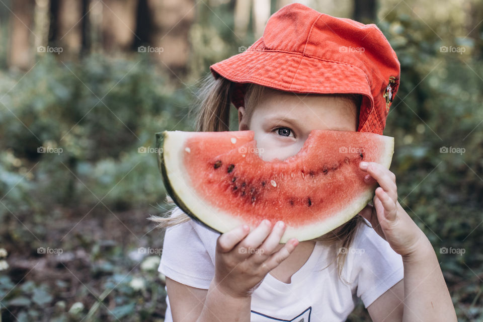 girl in a red hat eats watermelon