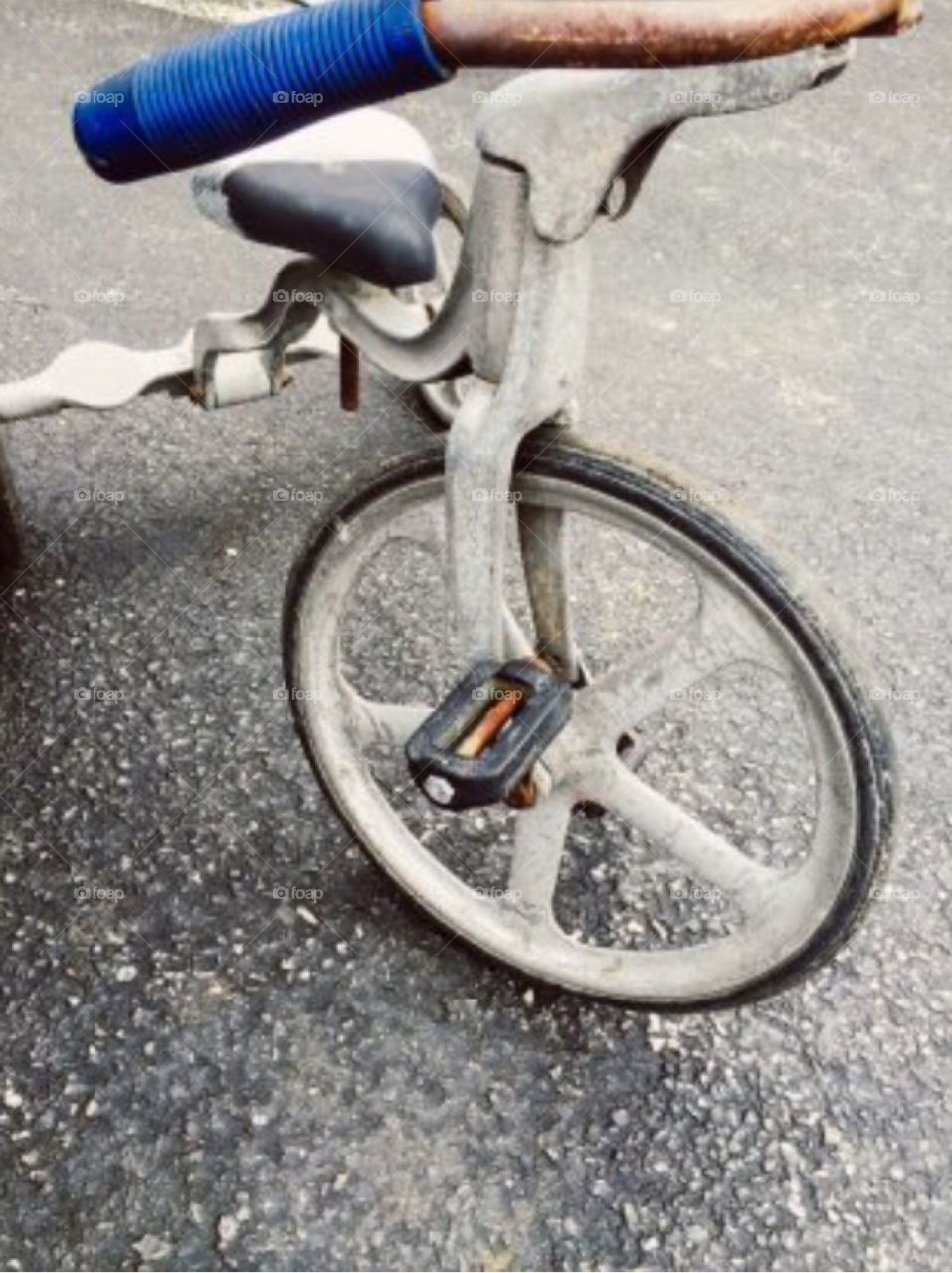 A rusted, antique Tricycle at a local flea market's parking lot