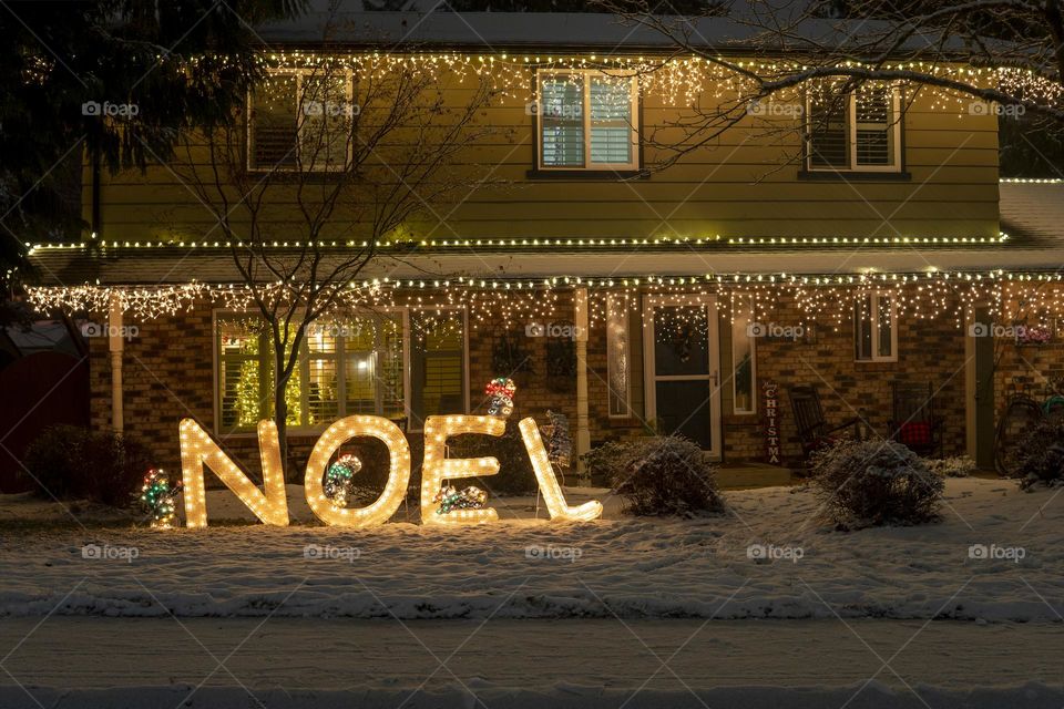 House decorated with yellow lights and Noel inscription