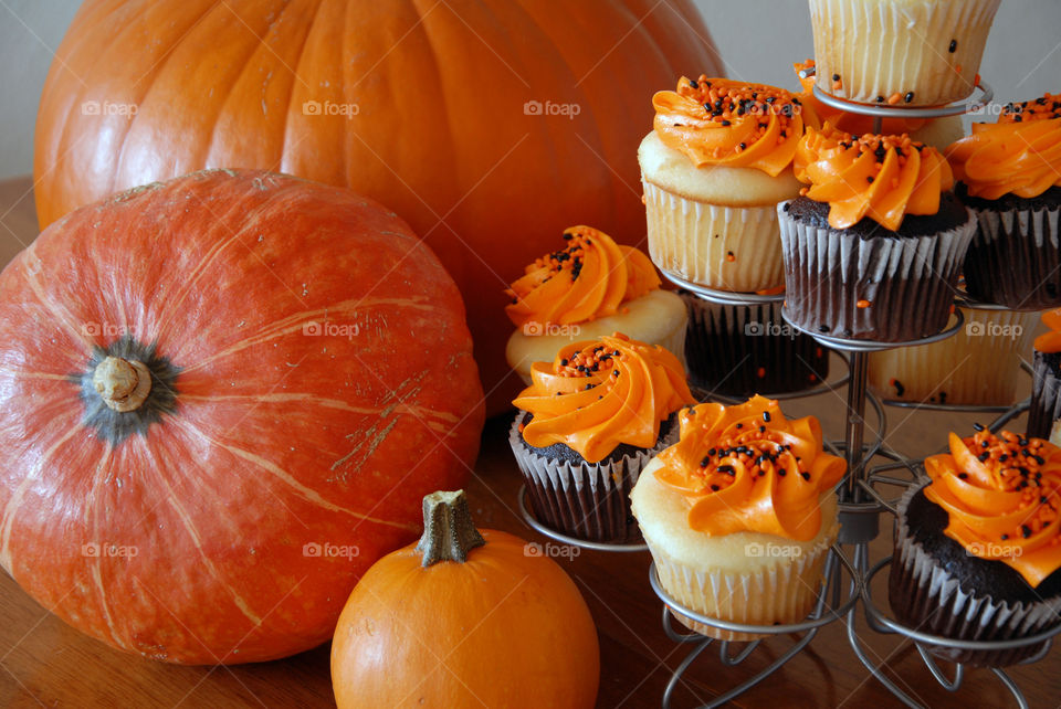 A table of orange pumpkins and vanilla and chocolate cupcakes ready for the Halloween party!