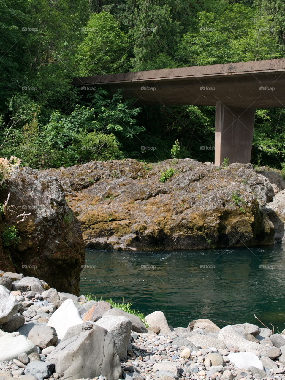 A bridge crossing over the beautiful Umpqua River flowing through its rocky banks in Southwestern Oregon. 