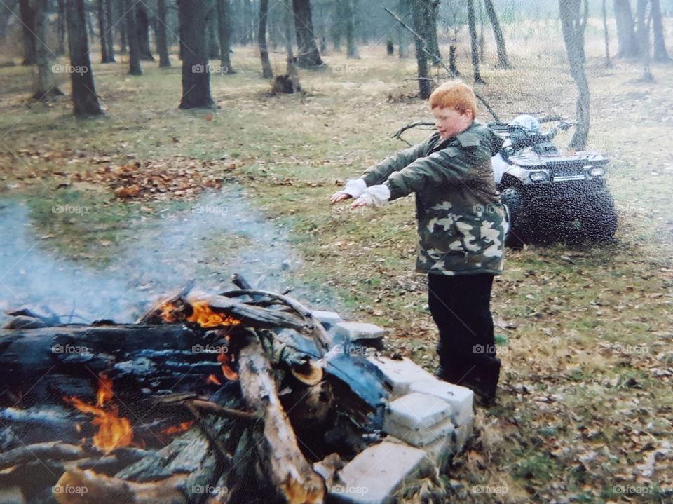 Boy warming up near the campfire