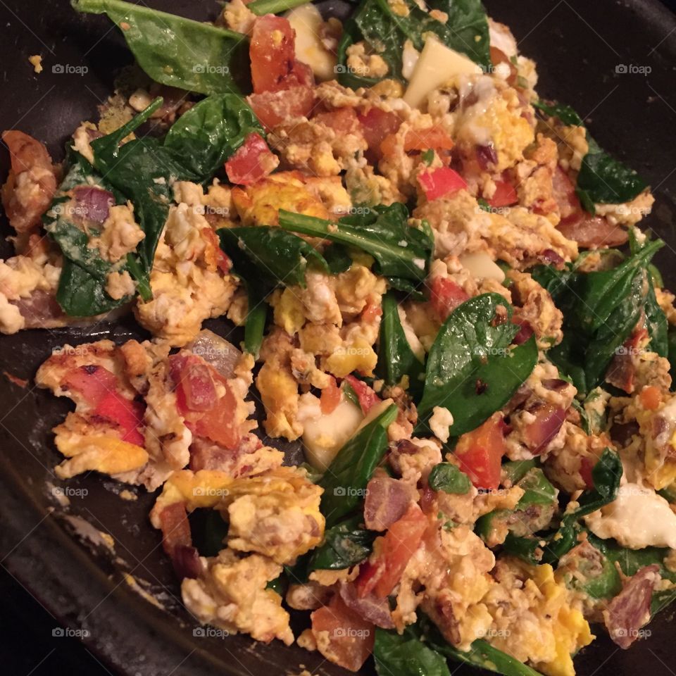 Scrambled eggs with tomatoes, onions, spinach, garlic, and cheese