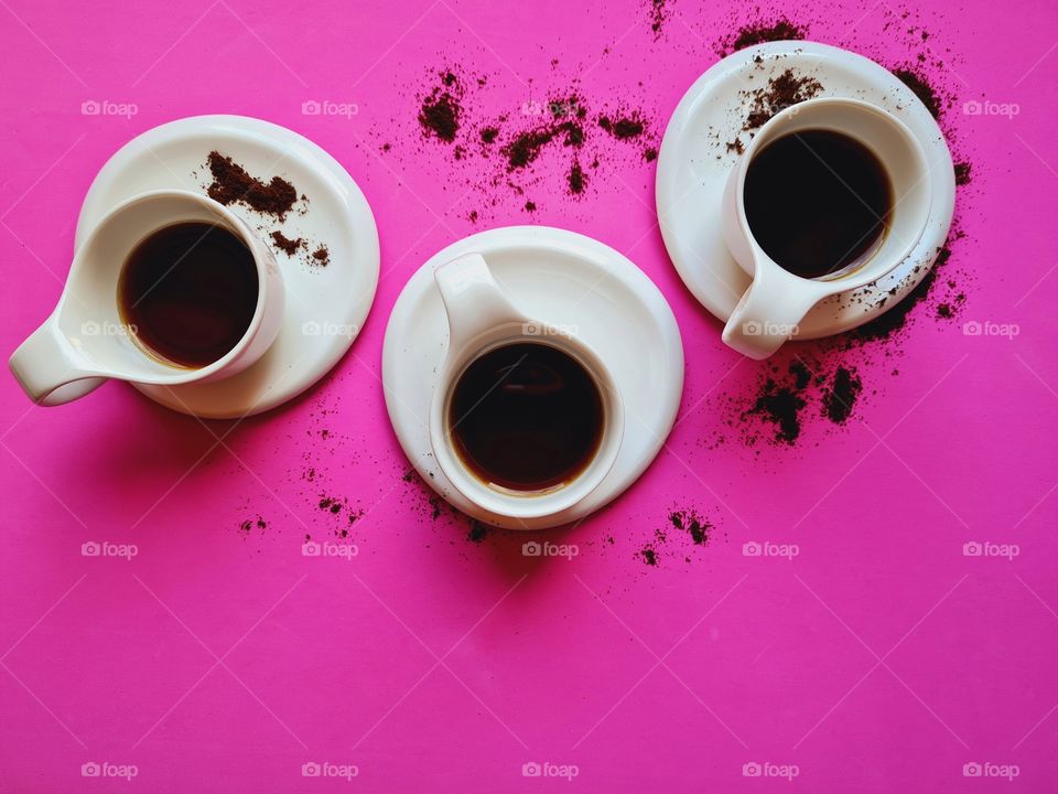 white coffee cups on pink background shot from above