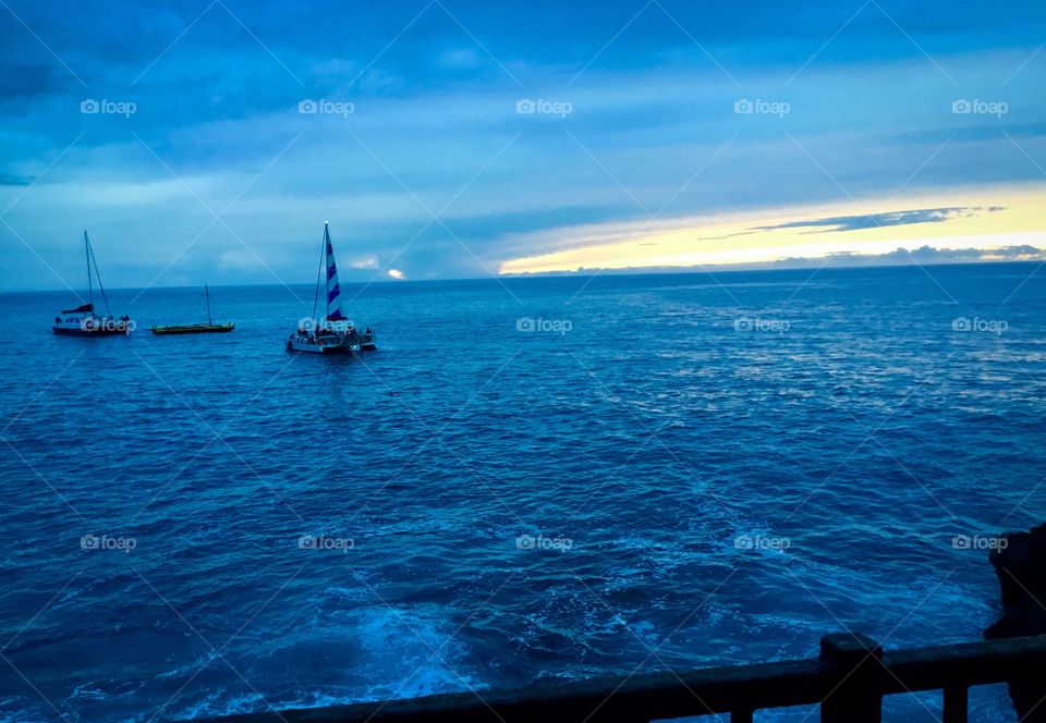 Boats on the water at dusk in Kona, Hawaii