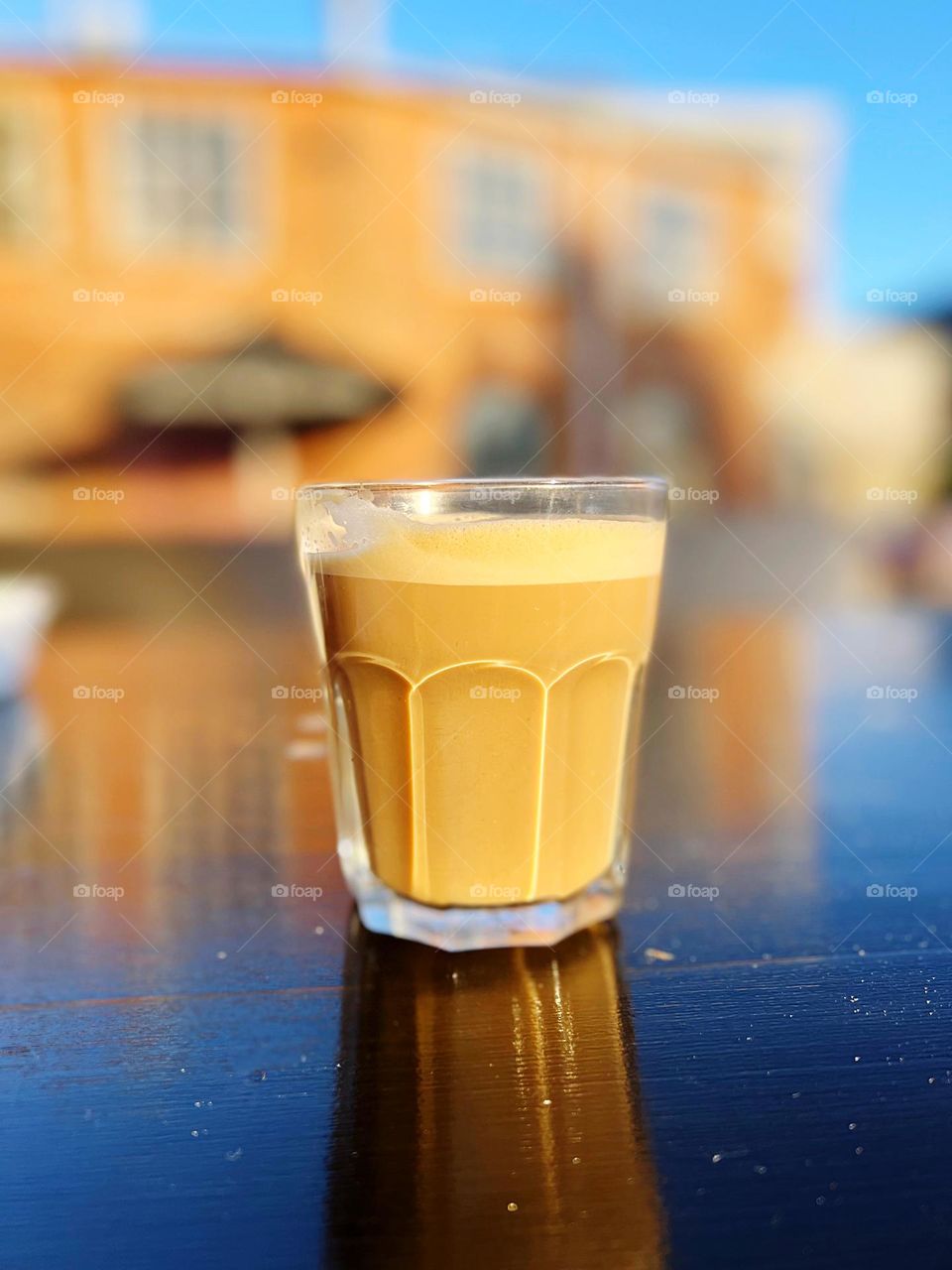 A cappuccino on a table outdoors in the sun