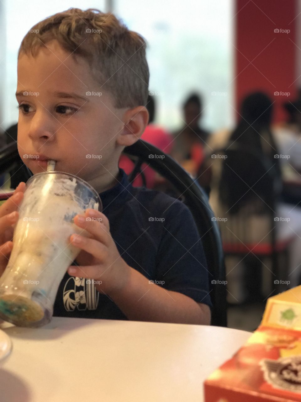 Little boy drinking milkshake in restaurant