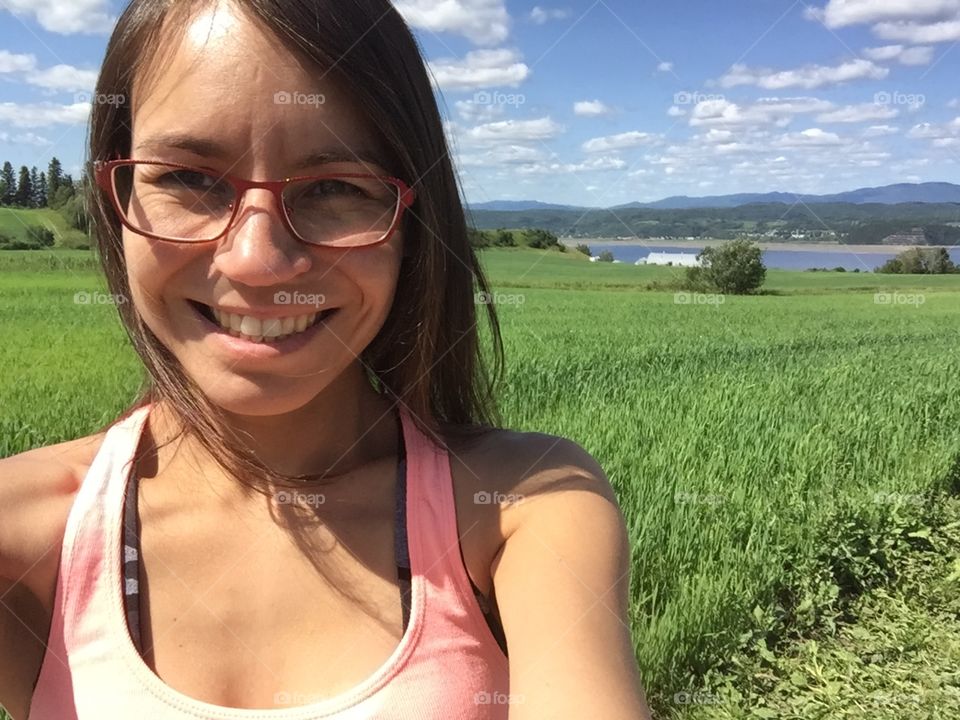 Girl wearing glasses in the field for self picking strawberries with the Saguenay fjord behind