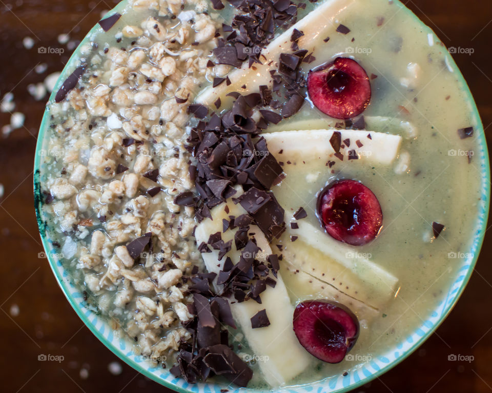 Full frame closeup of healthy fruit smoothie bowl with dark antioxidant rich chocolate,  cherries, banana, granola, coconut, chia seed artisanal healthy food photography 