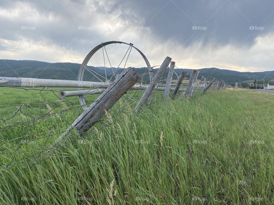 Irrigation Wheel Against a Fence in Wyoming with a Storm in the Mountains
