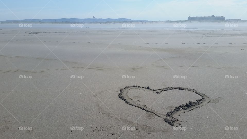 a little heart drawn into the sand on a beach