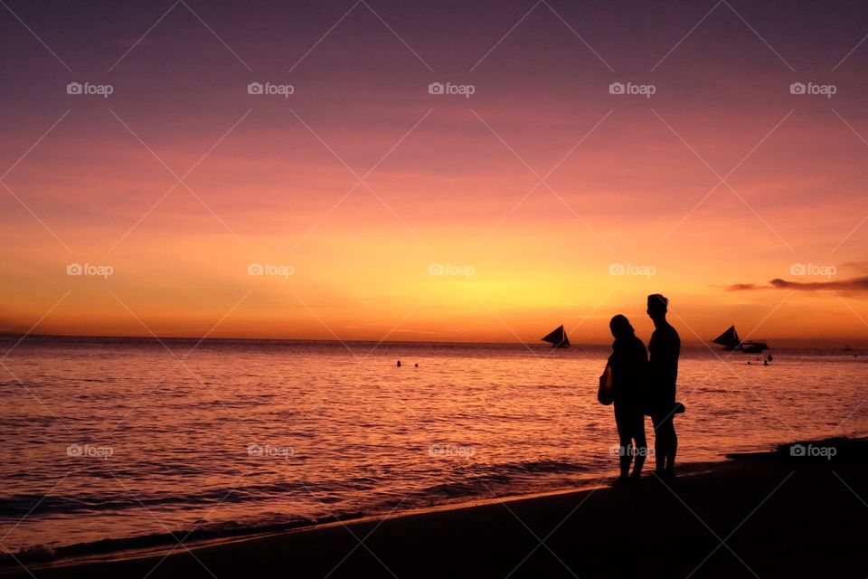 Couple looking at view of calm sea