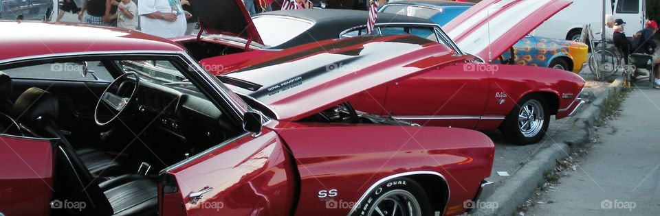 row of cars lined up for classic car show in California with open hoods