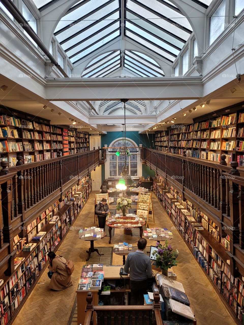 Bookstore with elegant architecture and interior design of wooden shelves and floors as well as glass ceiling.