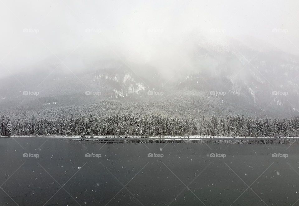 Moody winter lanscape on a snowy day at gray lake in mountains