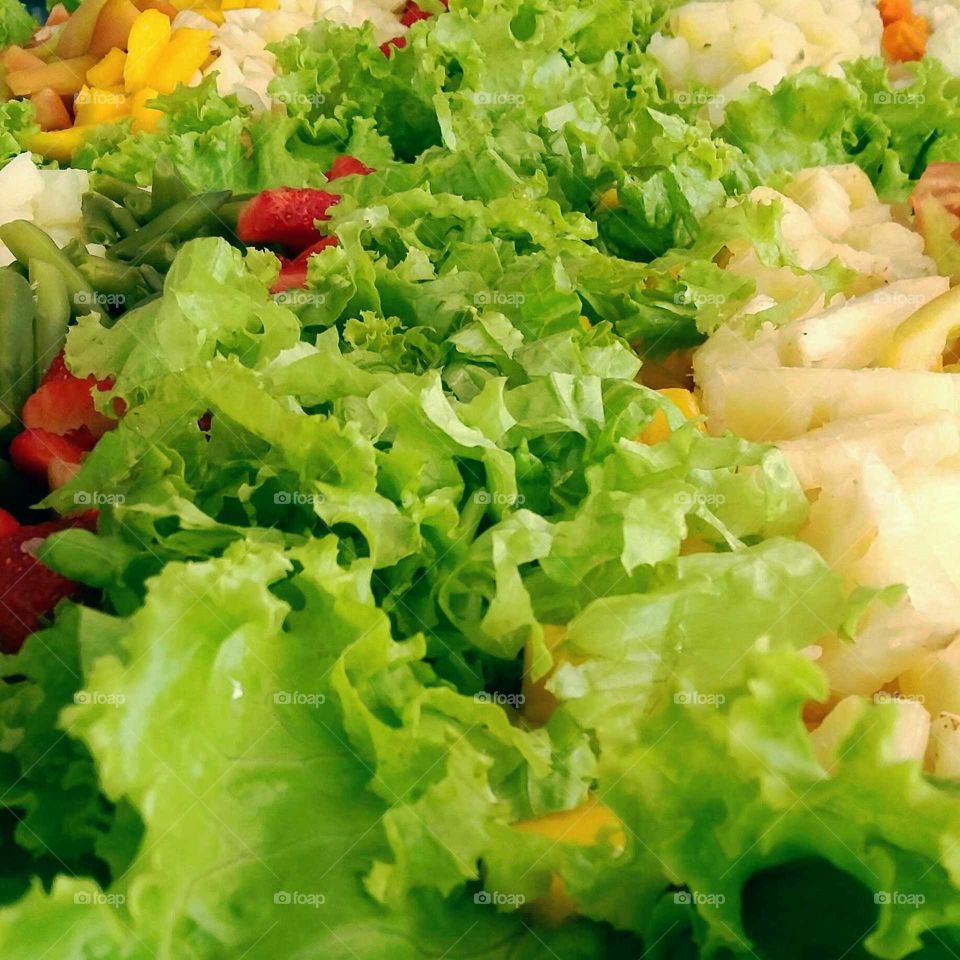 Salada de alface acompanhada por frutas coloridas e contrastantes.