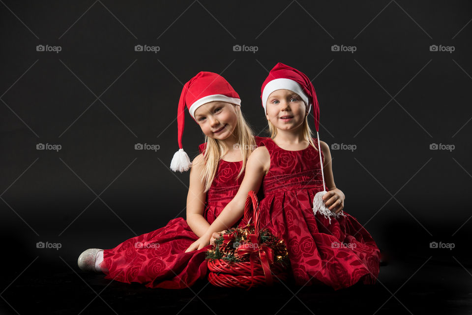 Four year old girl posing in santa dress for christmas.