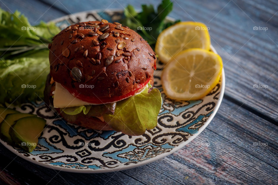 Dark burger with grain bread, cream cheese and avocado