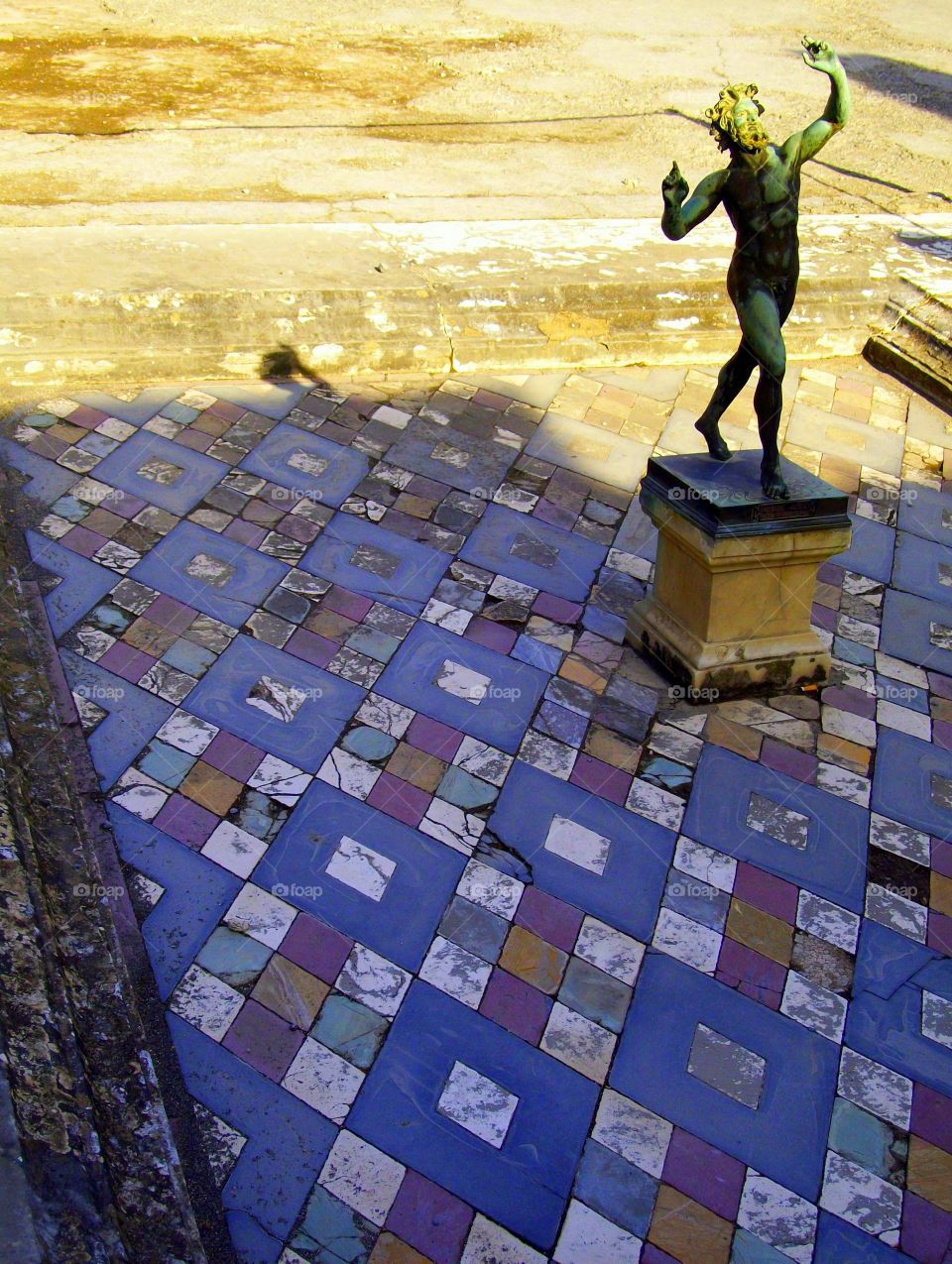 Restored statue and tile work in a small fountain amongst the ancient ruins of Pompeii