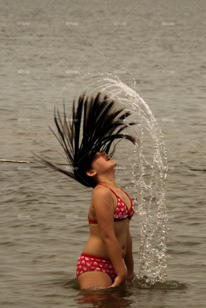 Teen girl throwing her hair back out of the water