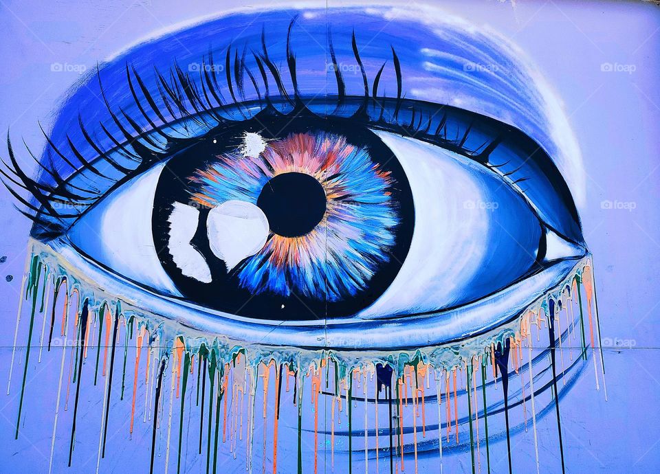 Outdoor art gallery art with an crying eye and the circle shaped iris and pupil.