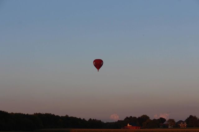 Hot air balloon high in the sky, above the meadows