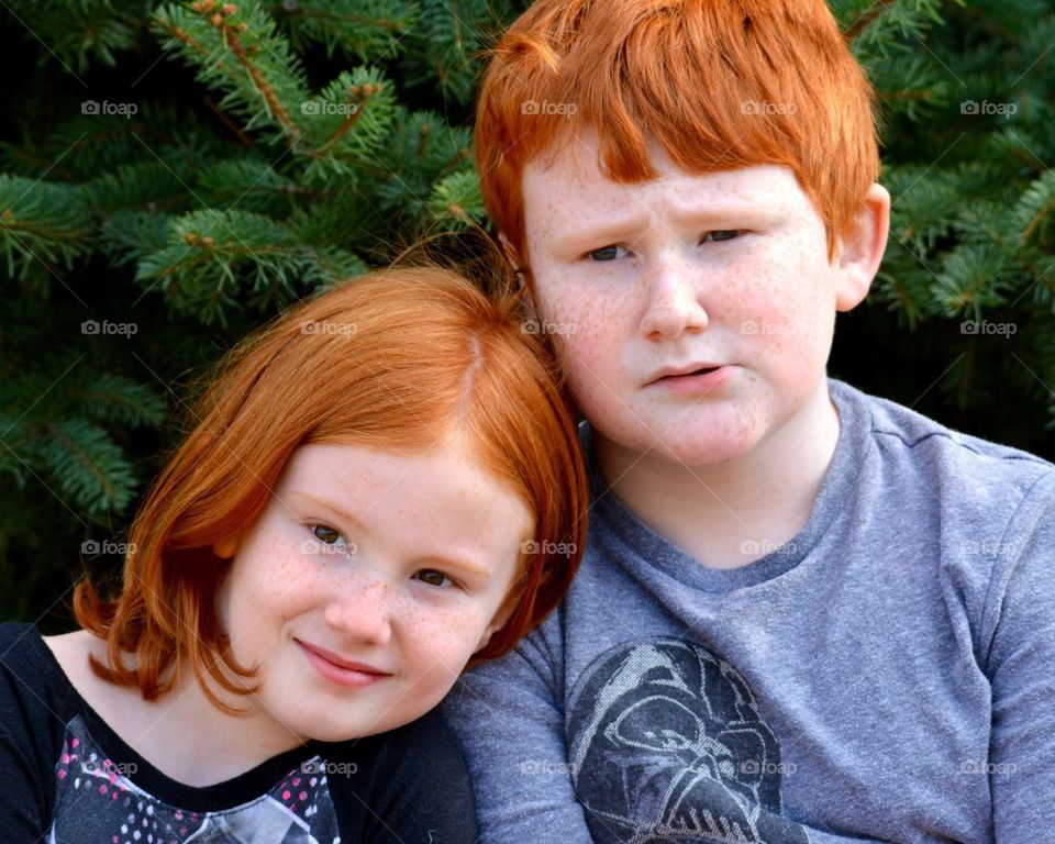 Portrait of redhead siblings smiling and close.