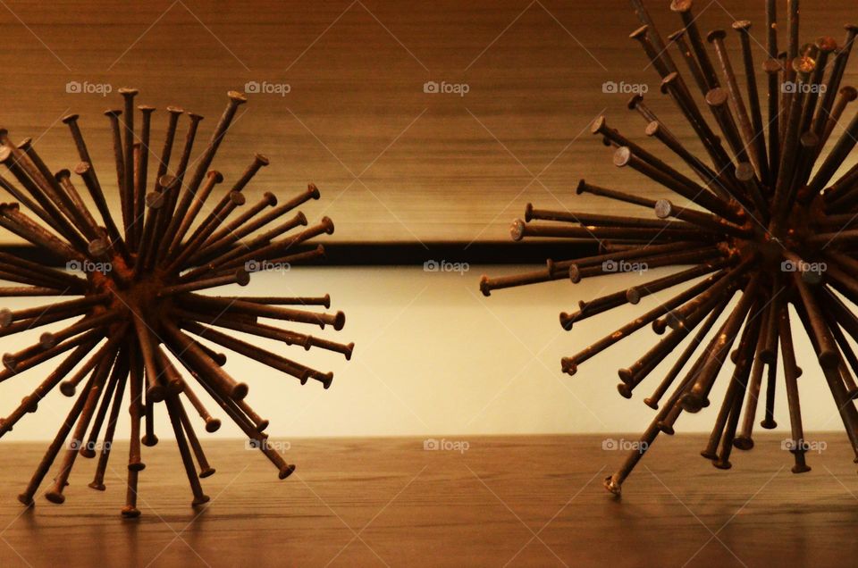 An art piece of metal rustic nails in the shape of a spherical sculpture rest on top of a bedroom dresser.