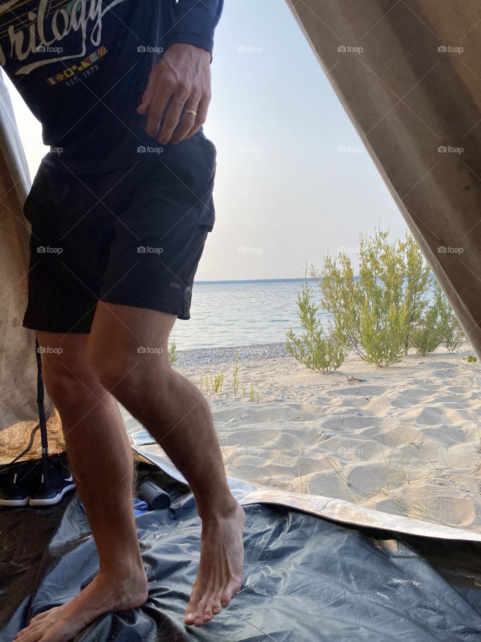 A man enters a tent on the beach.