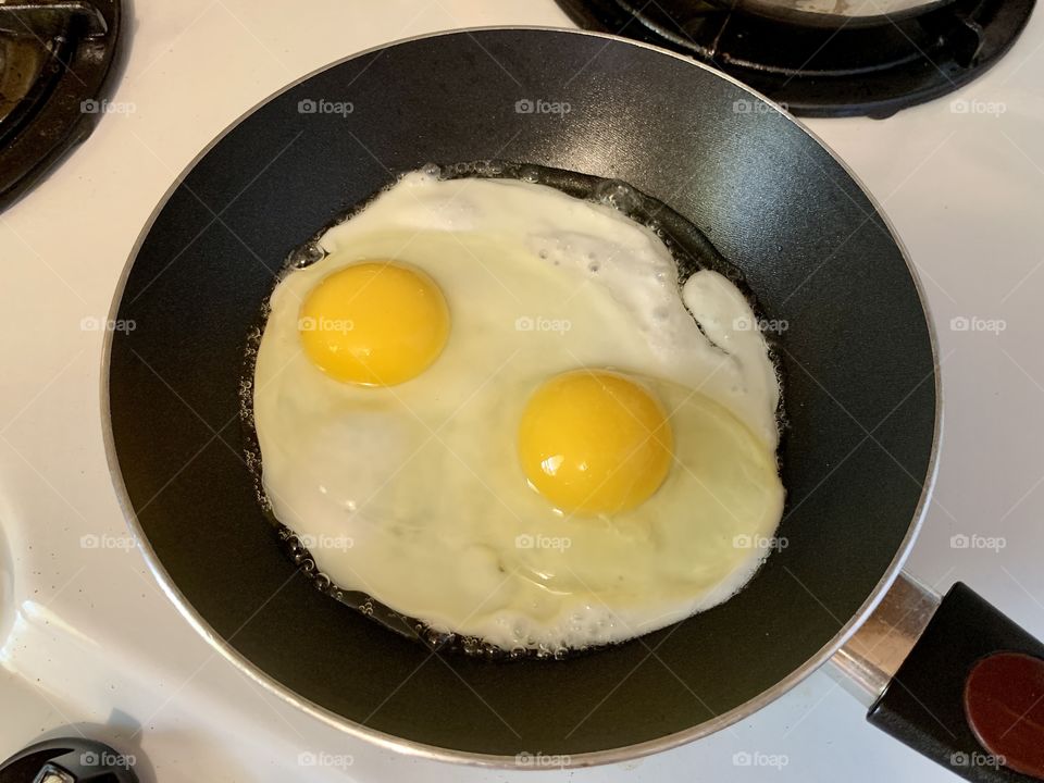 Egg drop in a black skillet for breakfast. Yellow egg yolk and egg white. High in protein.