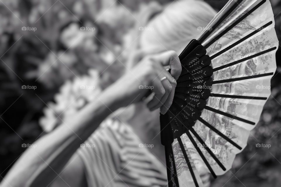 Black and white photo of a hand fan held by a woman