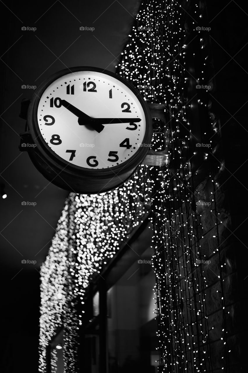 Street clock and sparkling fairy lights. Black and white photography. 