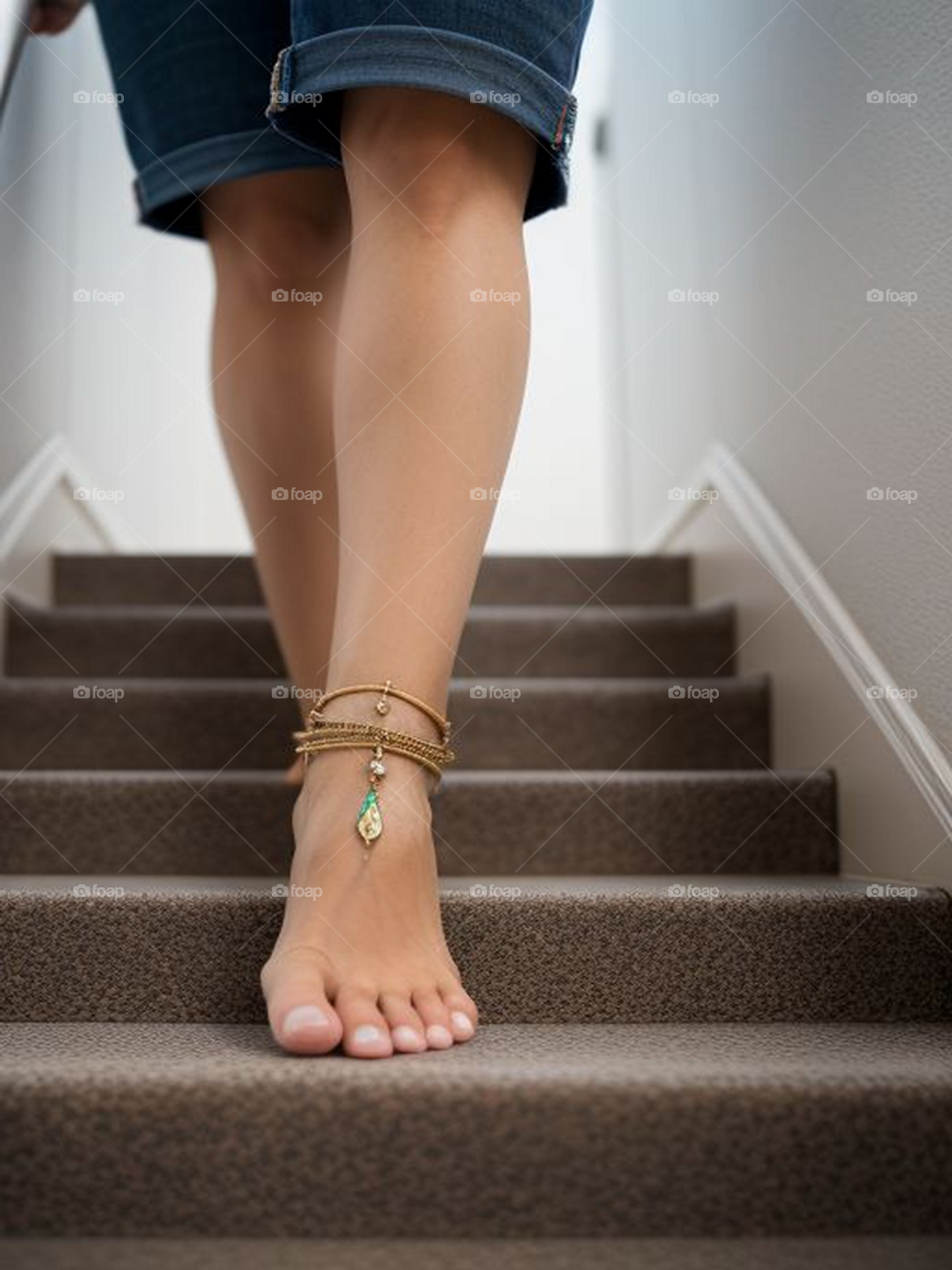Barefoot human feet descend the stairs