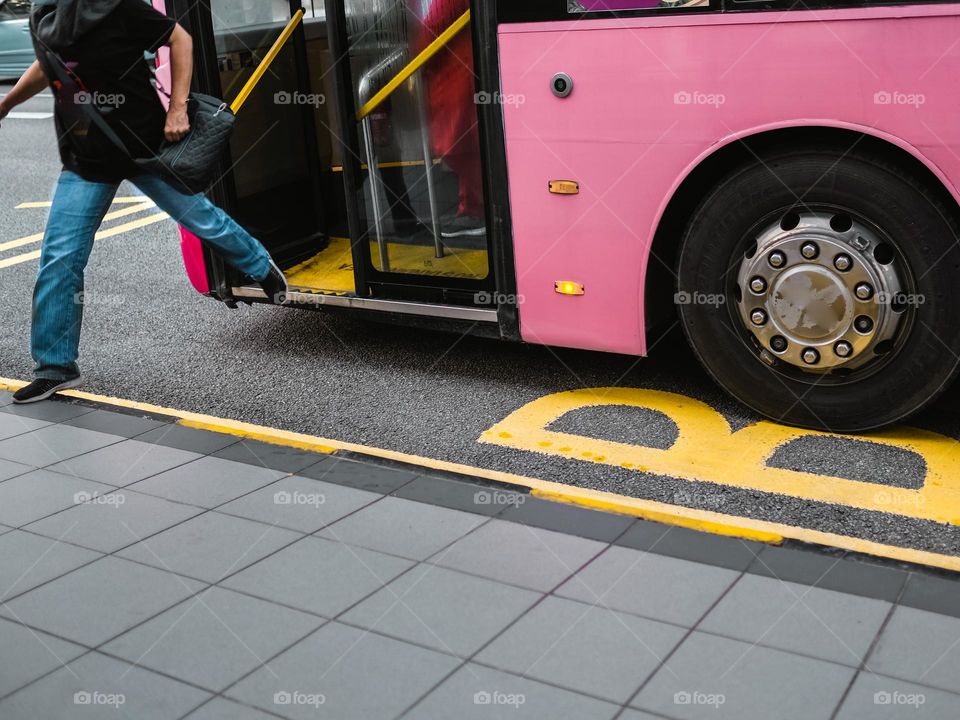 A person jumping off a pink bus