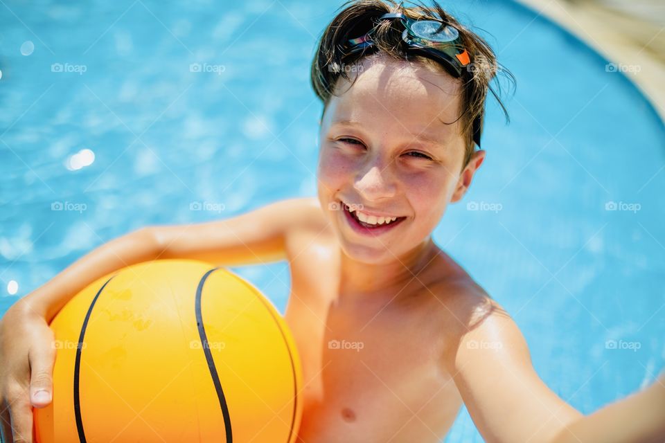 boy makes funny selfie in the pool