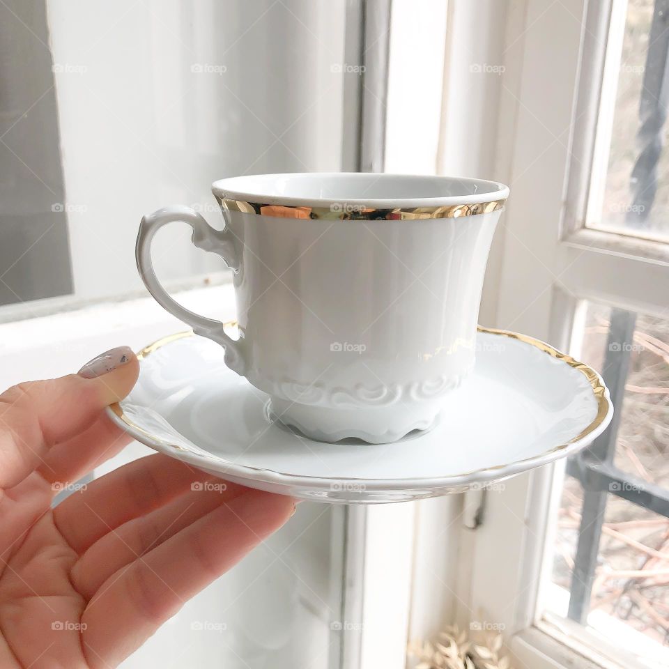 Old white vintage cup and saucer with relief ornament and golding