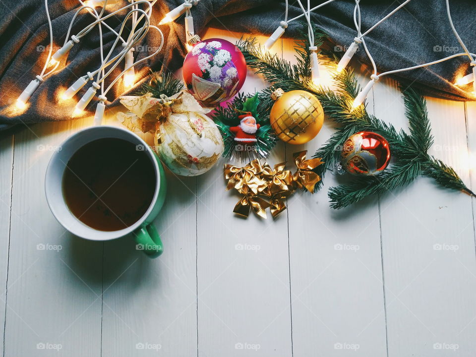 Christmas toys, a cup of hot tea and Christmas tree garland on a white table