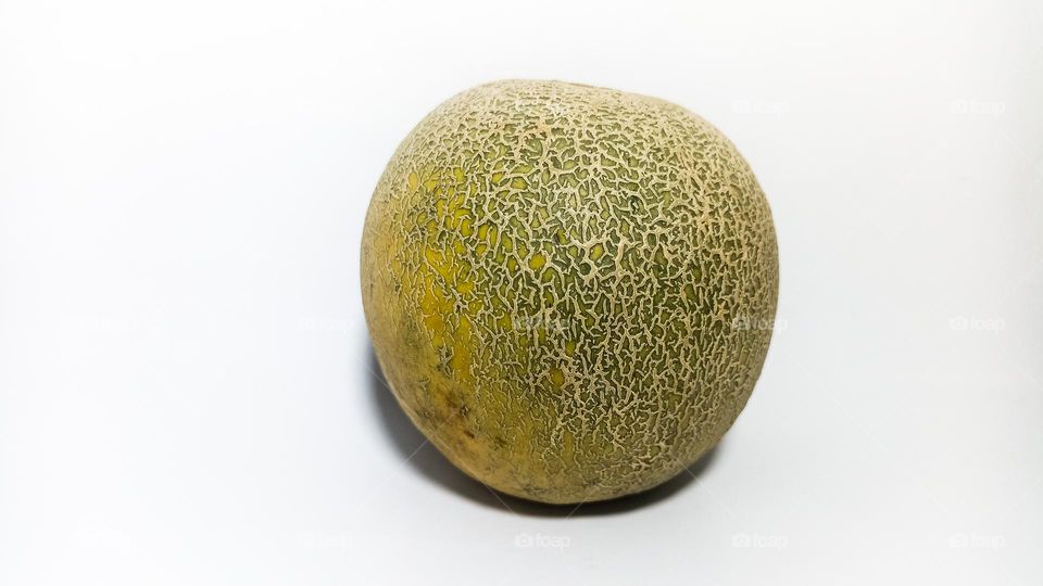 One whole round melon on an isolated white background in eye level view