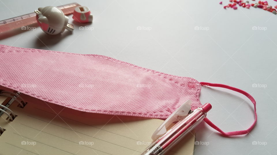 pink mask, pink pen, pink ruler, pink flash drive, and some pink marbles, all together around the table..