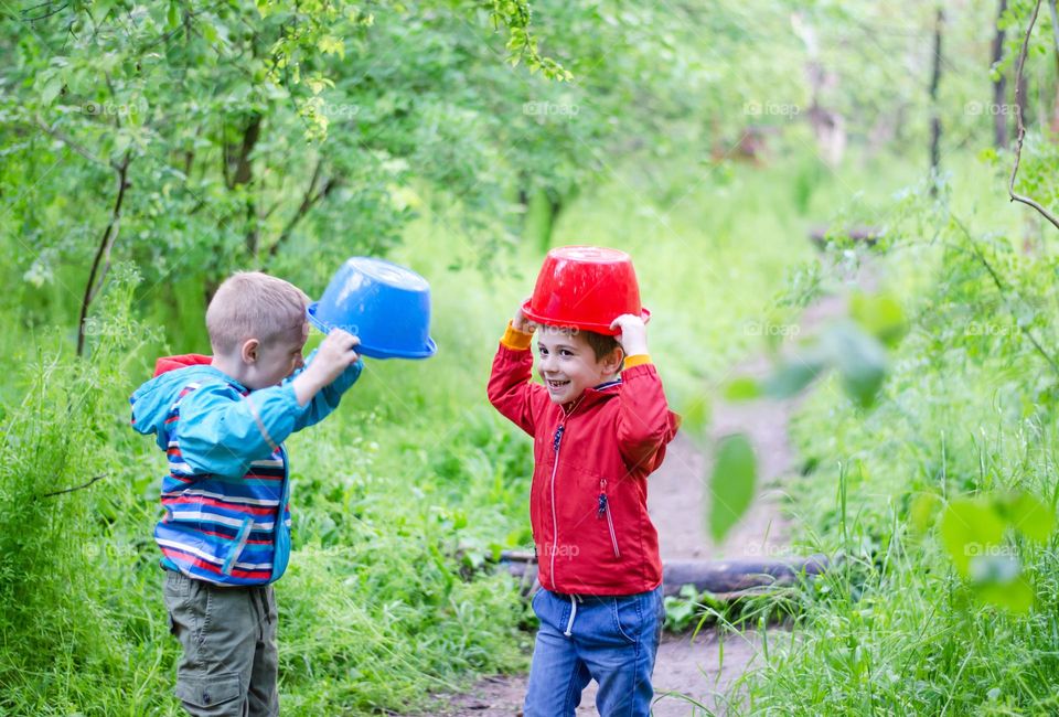 Children Playing in Rainy Spring Day with Buckets on Their Heads