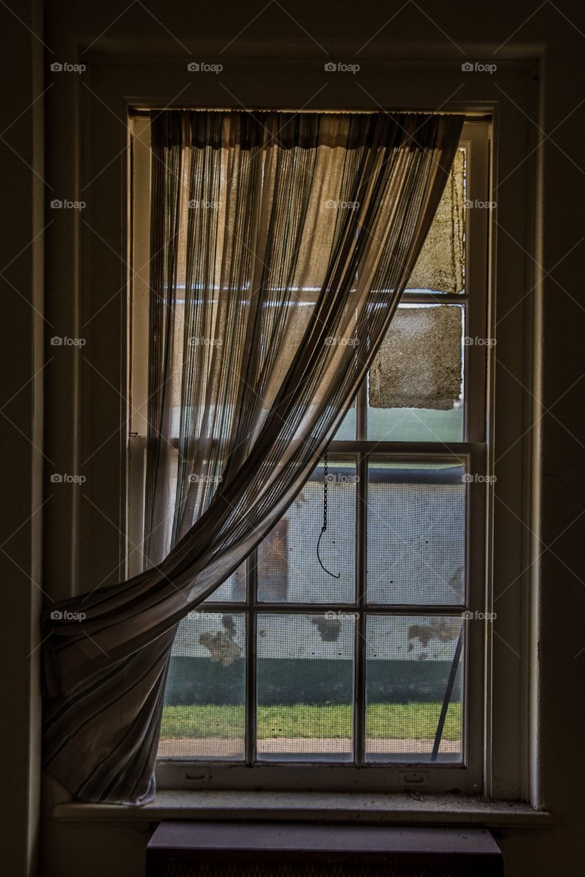 A dark window with a curtain half open