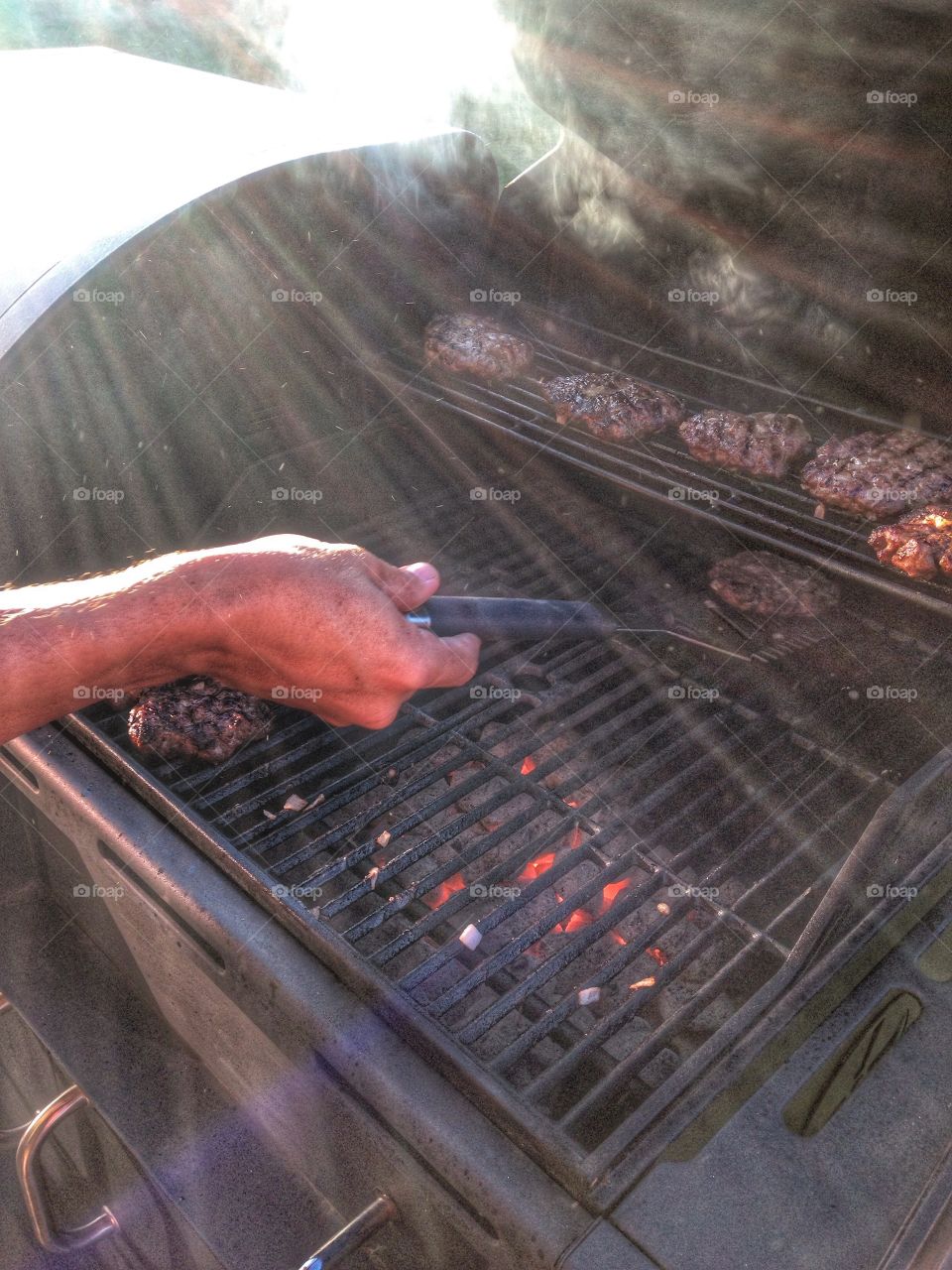 Flipping patties. Man flipping burgers on the grill