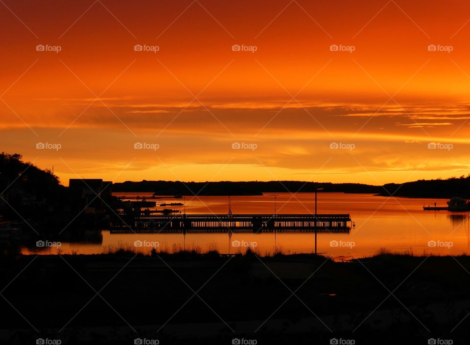 Silhouette of pier in sea at sunset