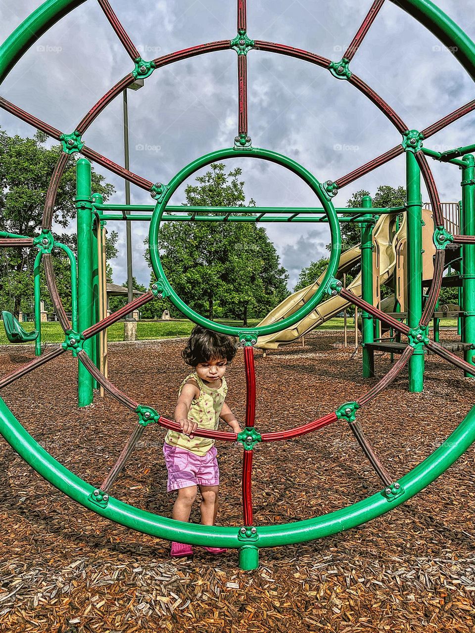 Toddler plays with circles at the park, metal climbing structure at the park, Metal circles to climb on at the local park, geometric shapes at the park, playing outdoors with toddlers, finding shapes at the park