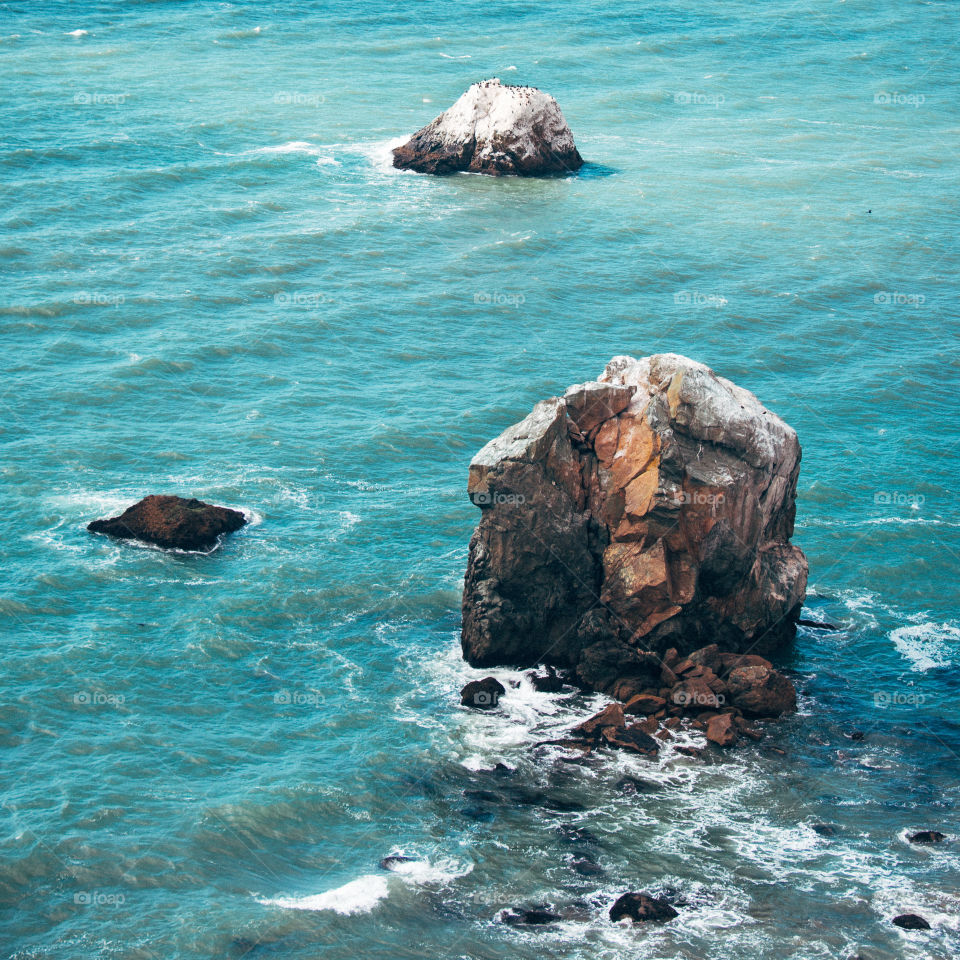 California water rocks on the warm colorful beach in San Francisco. Waves hit stones in the salty fresh air summer spring breeze.